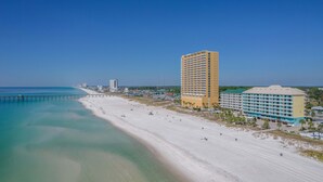 A coastal hotel with a beach view, a pier, and a large building with multiple balconies. - Holiday Terrace Beachfront Hotel, a By The Sea Resort (Panama City Beach)