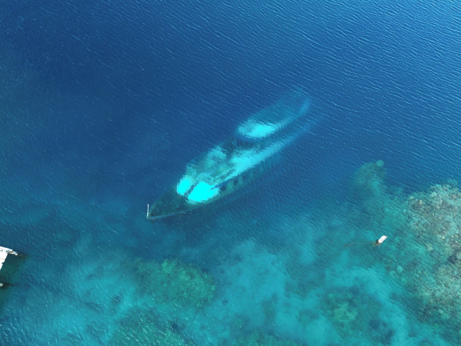 A clear view of a boat on a calm sea with a coral reef in the background.