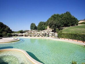 Una piscina al aire libre de temporada, sombrillas