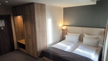 A bedroom with a bed, bedside tables, a wardrobe, and a wall-mounted lamp.