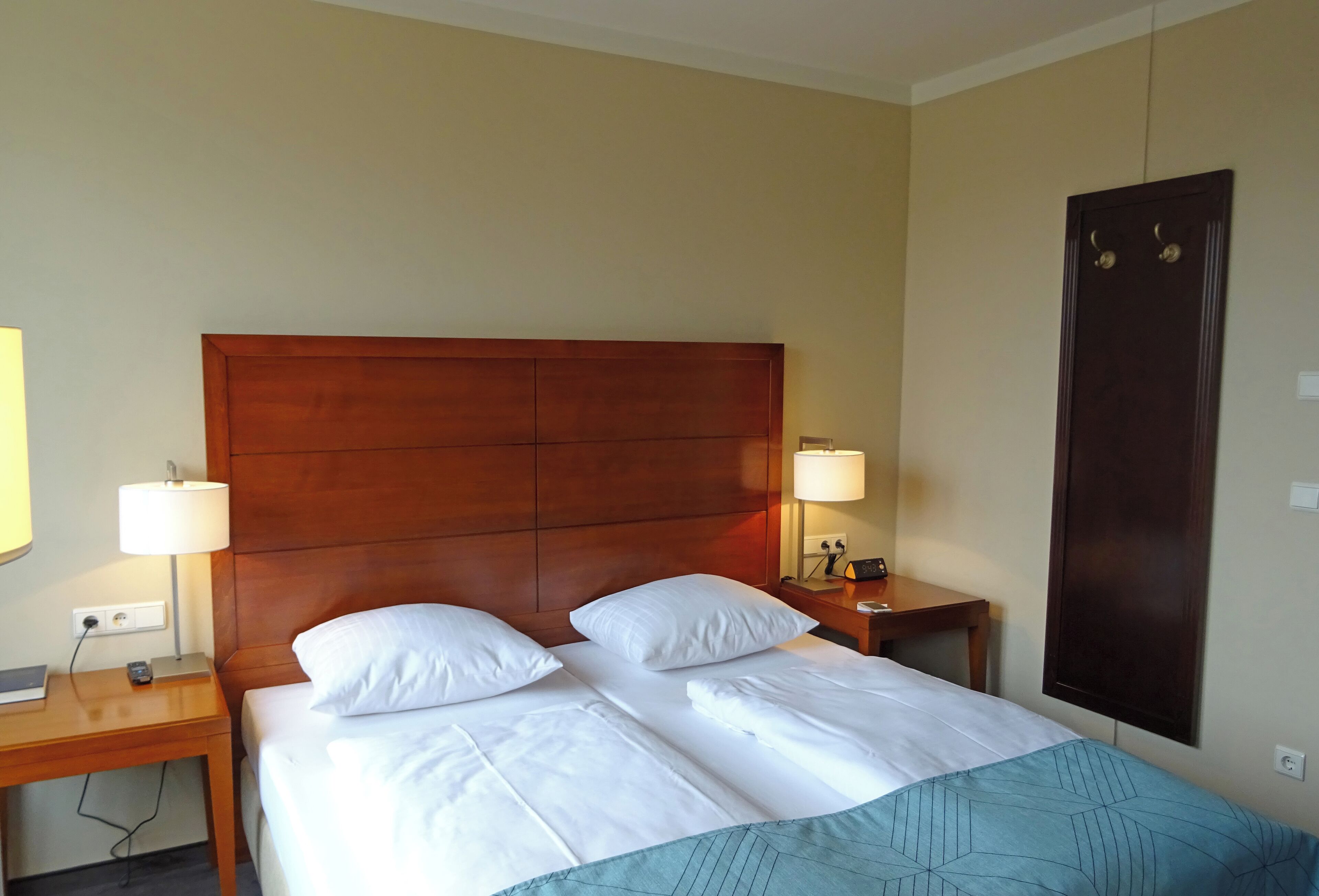 A hotel room with a large bed, two bedside tables, and a wooden headboard.
