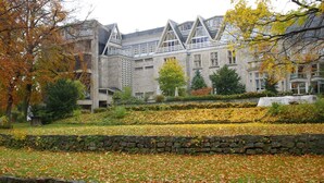 A building with a stone facade and multiple windows, surrounded by a landscaped garden with trees and a stone wall. - St.-Michaels-Heim Hotel (Berlin)