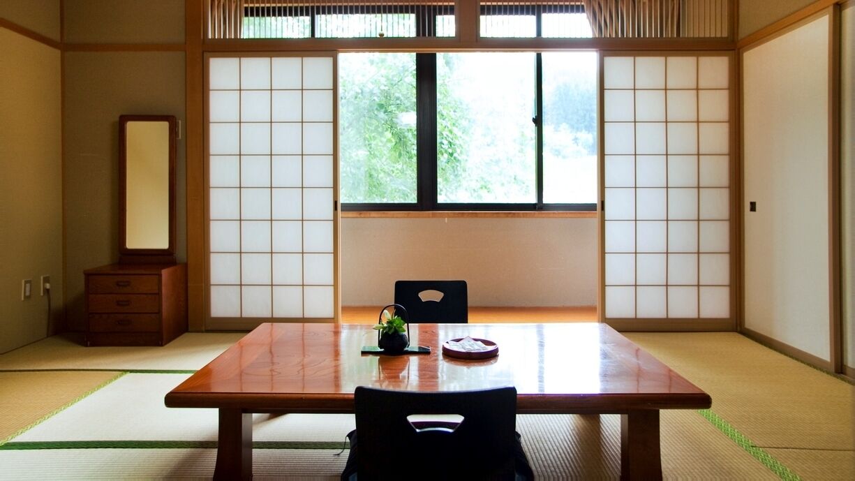 A traditional Japanese room with tatami flooring, a low table, a chair, and shoji screens.