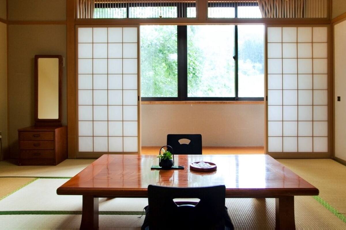 A traditional Japanese room with tatami flooring, a low table, a chair, and shoji screens.