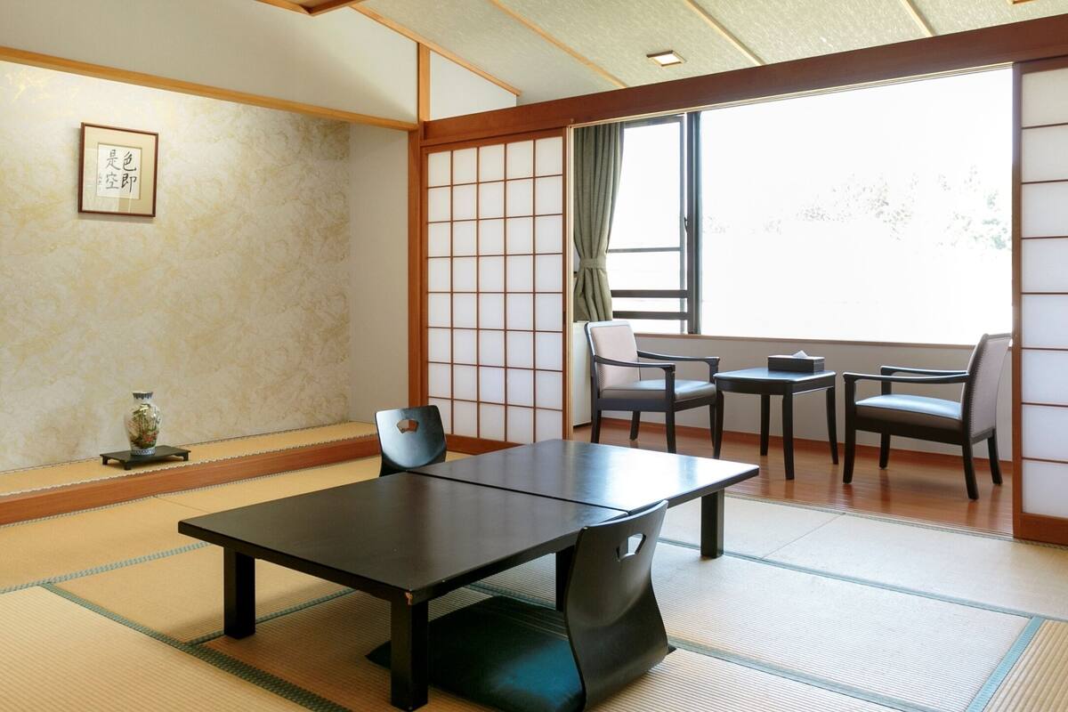 A traditional Japanese room with tatami flooring, a low table, and sliding doors.