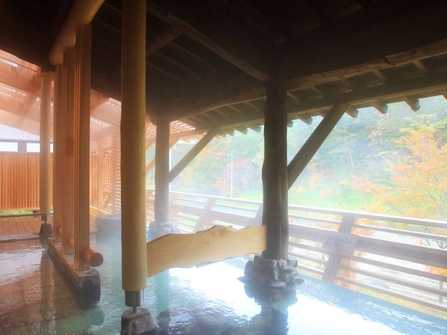 A wooden structure with a view of autumn foliage through a glass window.