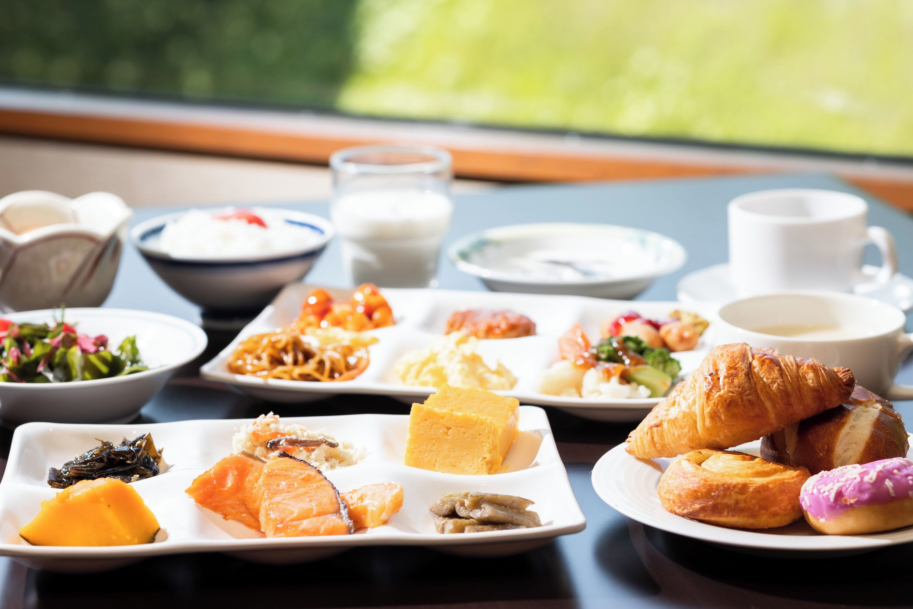 Una mesa con diversos platos, incluyendo mariscos, pasteles y un croissant.
