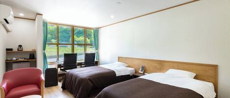 A hotel room with two beds, a desk, a chair, and a small table.