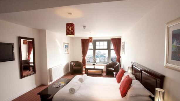 A hotel room with a large bed, two chairs, a table, and a window with curtains. - Park Central Hotel (Bournemouth)