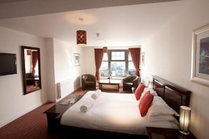 A hotel room with a large bed, two chairs, a table, and a window with curtains. - Park Central Hotel (Bournemouth)
