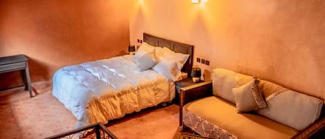 A cozy bedroom with a bed, a sofa, and a nightstand.