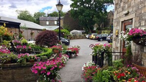A street with a restaurant and a white tent. There are cars parked on the street and flowers along the sidewalk. - The Old Bell Inn (Oldham)