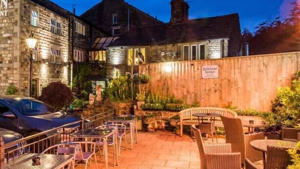 A courtyard with outdoor seating, stone buildings, and a sign for a botanical garden. - The Old Bell Inn (Oldham)