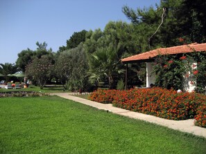 A garden with a pathway, a gazebo, and various trees. - Denizati Holiday Village (Menderes)
