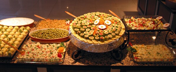Un bufé con diversos platos, incluyendo arroz, vegetales y una gran pieza central.