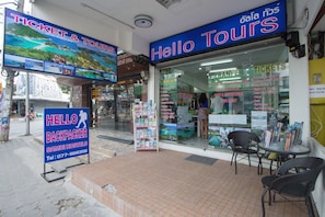 A storefront with a sign reading "Hello Tours" and a signboard for "Samui Hostels" with a contact number.
