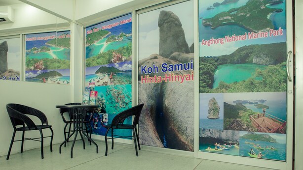 A room with a glass wall displaying posters of Koh Samui and Hinta-Hinyai, a table, and two chairs. - Hello Backpacker Samui Hostel (Koh Samui)