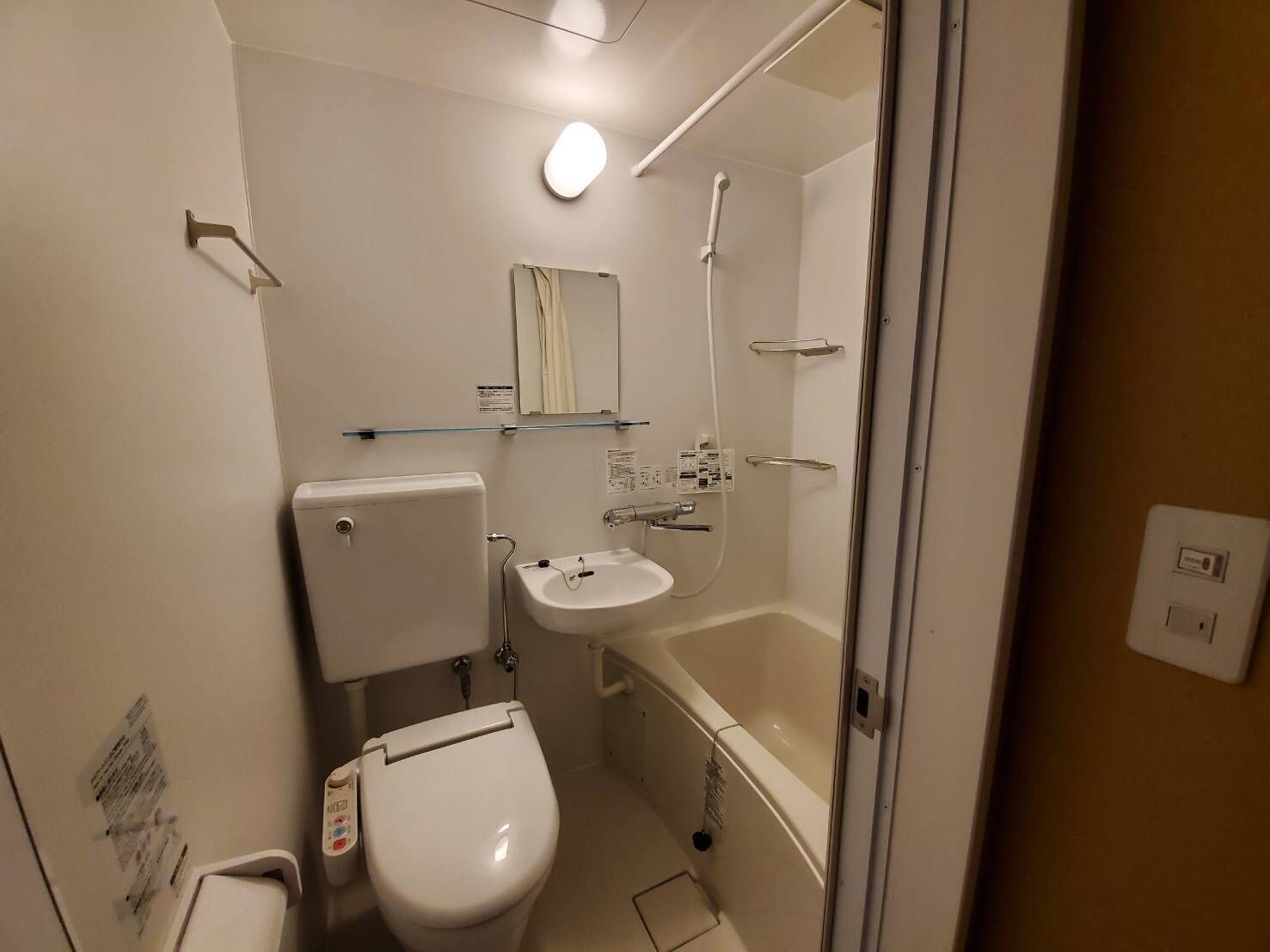 A compact bathroom with a toilet, sink, and shower.