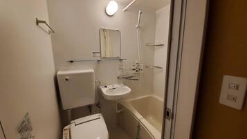 A compact bathroom with a toilet, sink, and shower.