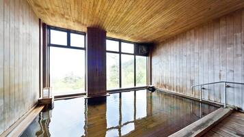 Un interior de madera con una amplia piscina cubierta, paredes de madera y grandes ventanales.