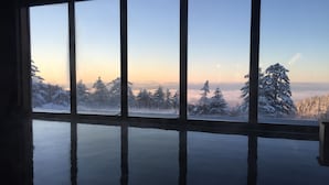 Una habitación con un ventanal grande que ofrece vistas a un paisaje nevado con árboles y cielo despejado.