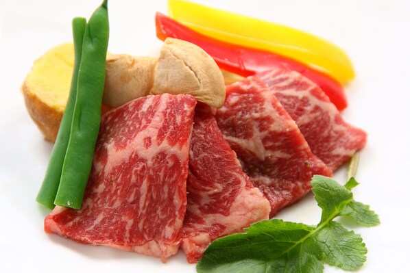 A plate of raw beef, green beans, and slices of bell pepper.