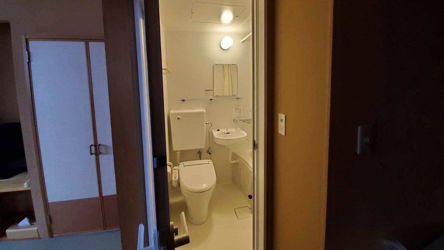 Een badkamer met toilet, wastafel en spiegel.