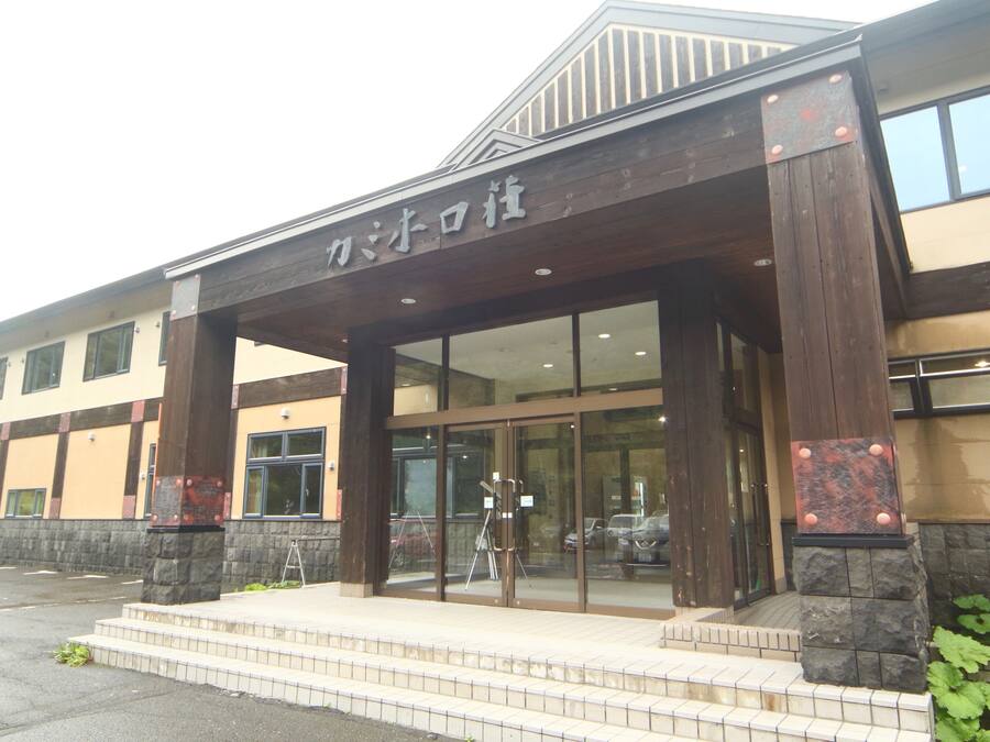 A building with a wooden entrance canopy and stone pillars.