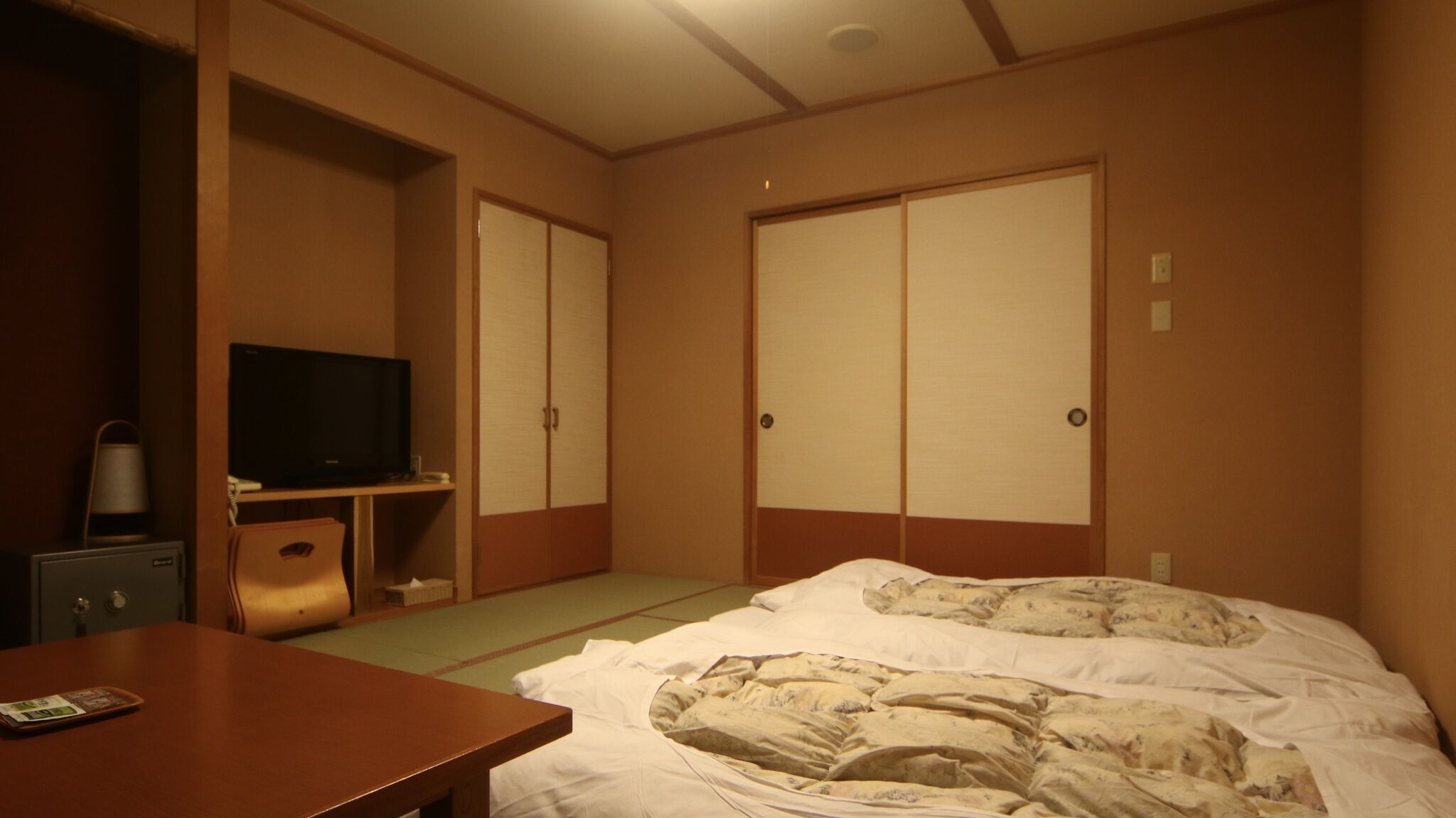 Een hotelkamer met een bed, een televisie, een bureau en een kledingkast.