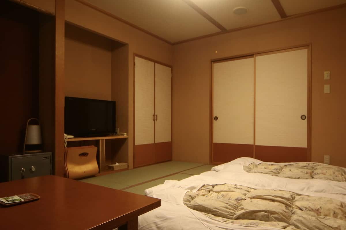 A hotel room with a bed, a TV, a desk, and a wardrobe.