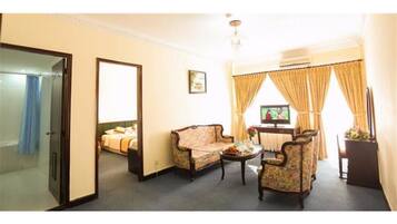 A hotel room with a sofa set, a television, and a small table.