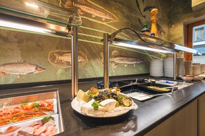A buffet with various food items and a fish mural on the wall. - Fish'Inn Zell - Hotel Fischerwirt (Zell am See)