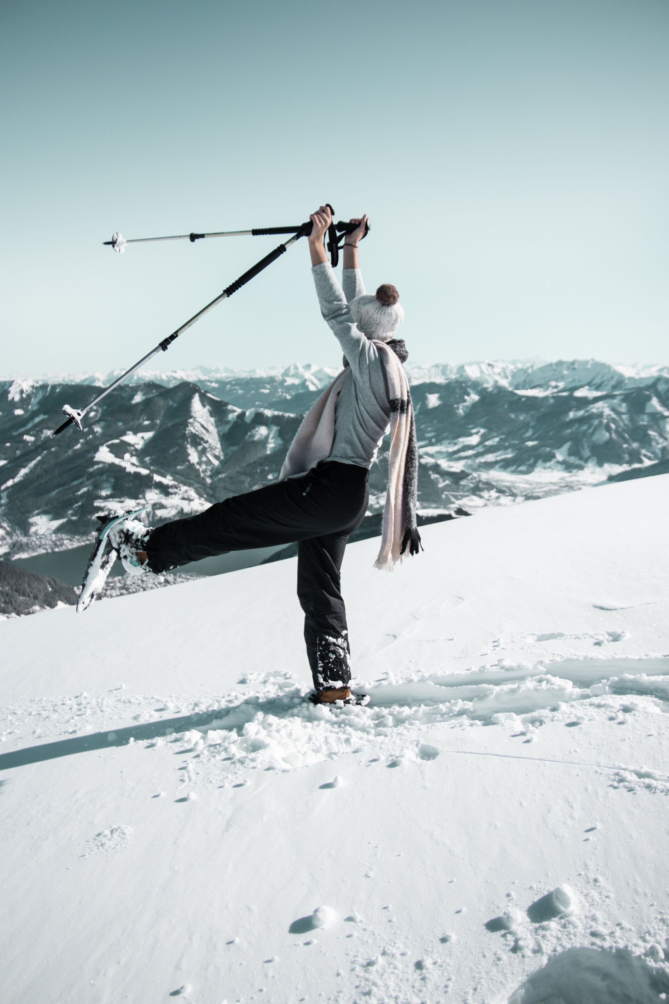 A person performing a yoga pose on a snowy mountain with a clear sky and snow-covered peaks in the background.