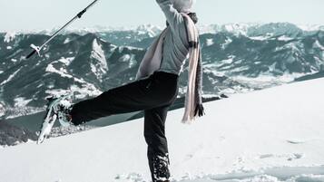 A person performing a yoga pose on a snowy mountain with a clear sky and snow-covered peaks in the background.