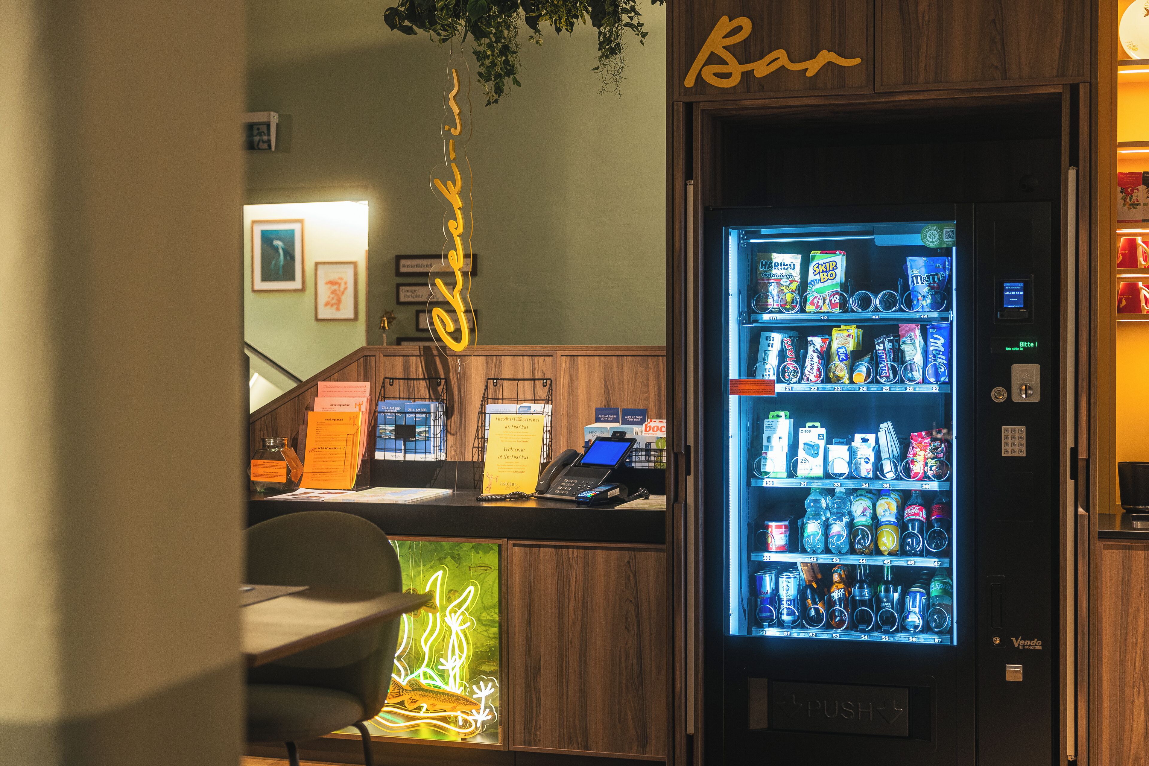 Een bar, een neonbord, een automaat en een receptiebalie met een computer en telefoon.
