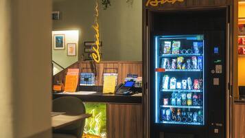 Een bar, een neonbord, een automaat en een receptiebalie met een computer en telefoon.