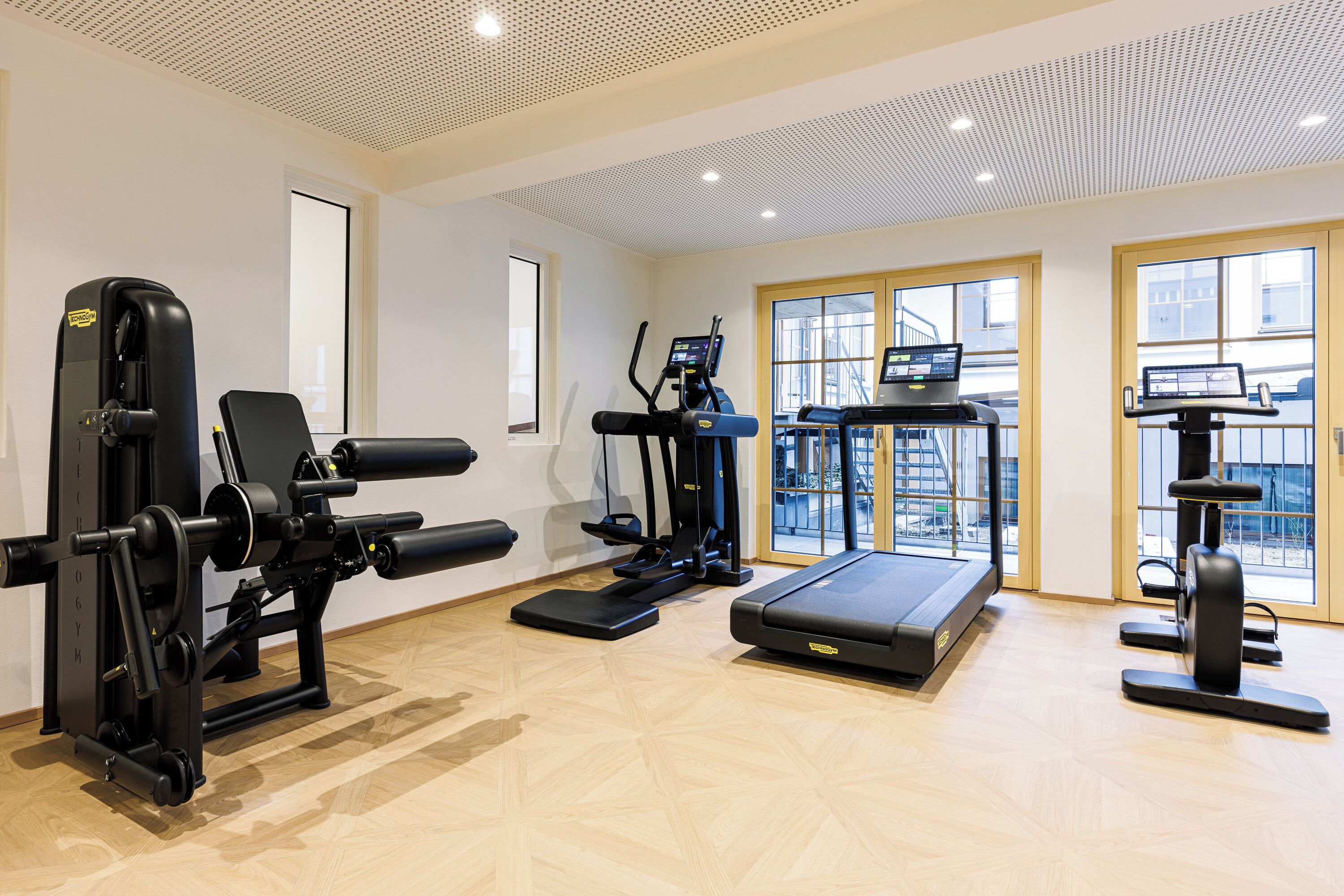 Ein Fitnessstudio mit verschiedenen Trainingsgeräten, darunter Laufband, Crosstrainer und Kraftgeräte.