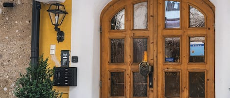 L’entrée du Fish’n Inn se distingue par une porte à double battant en bois, une grande plante en pot et un mur en pierre.