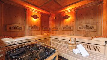 Un sauna avec des bancs en bois, un bassin en pierre et une serviette.