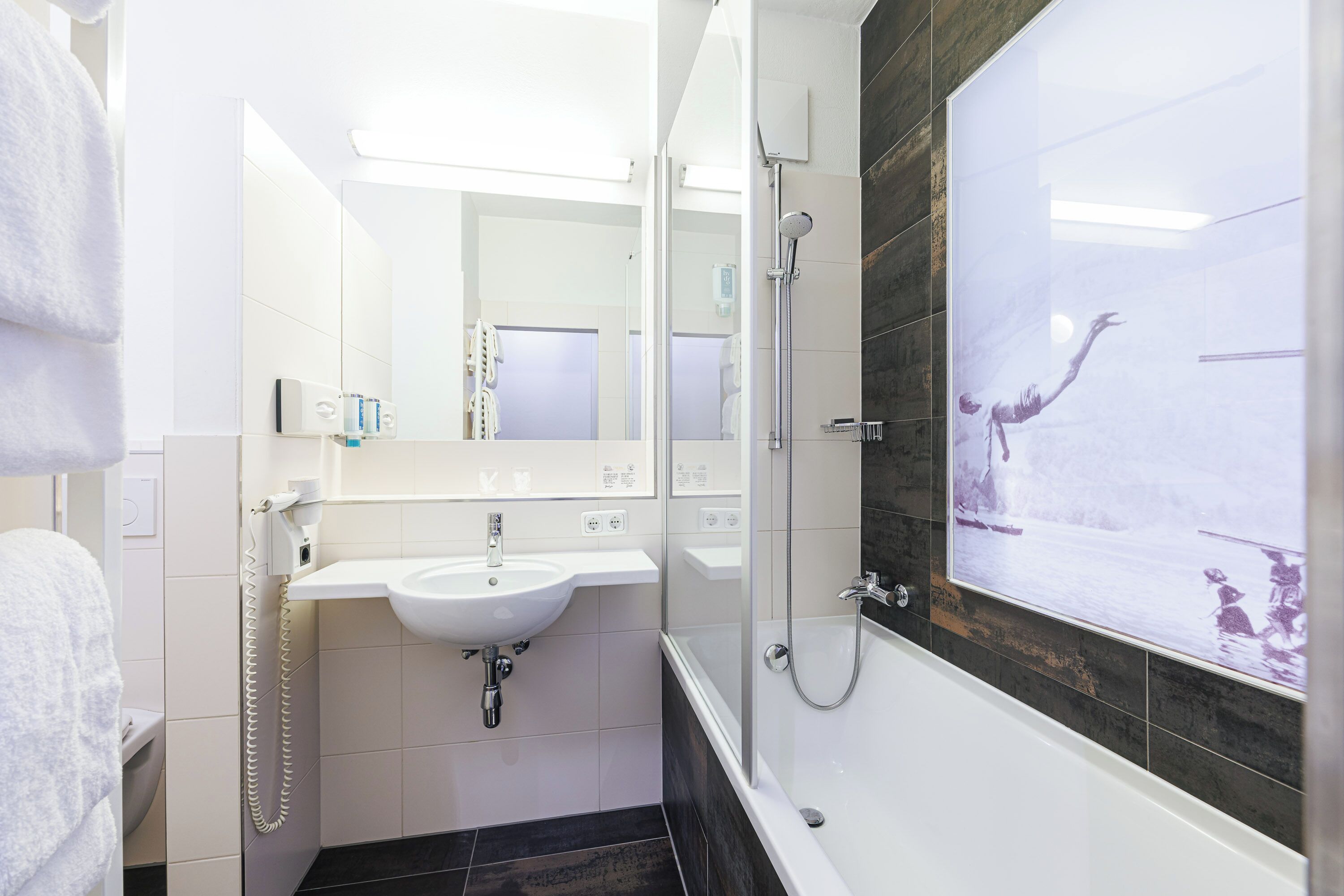 A modern bathroom with a white sink, a glass-enclosed shower, and a large mirror.