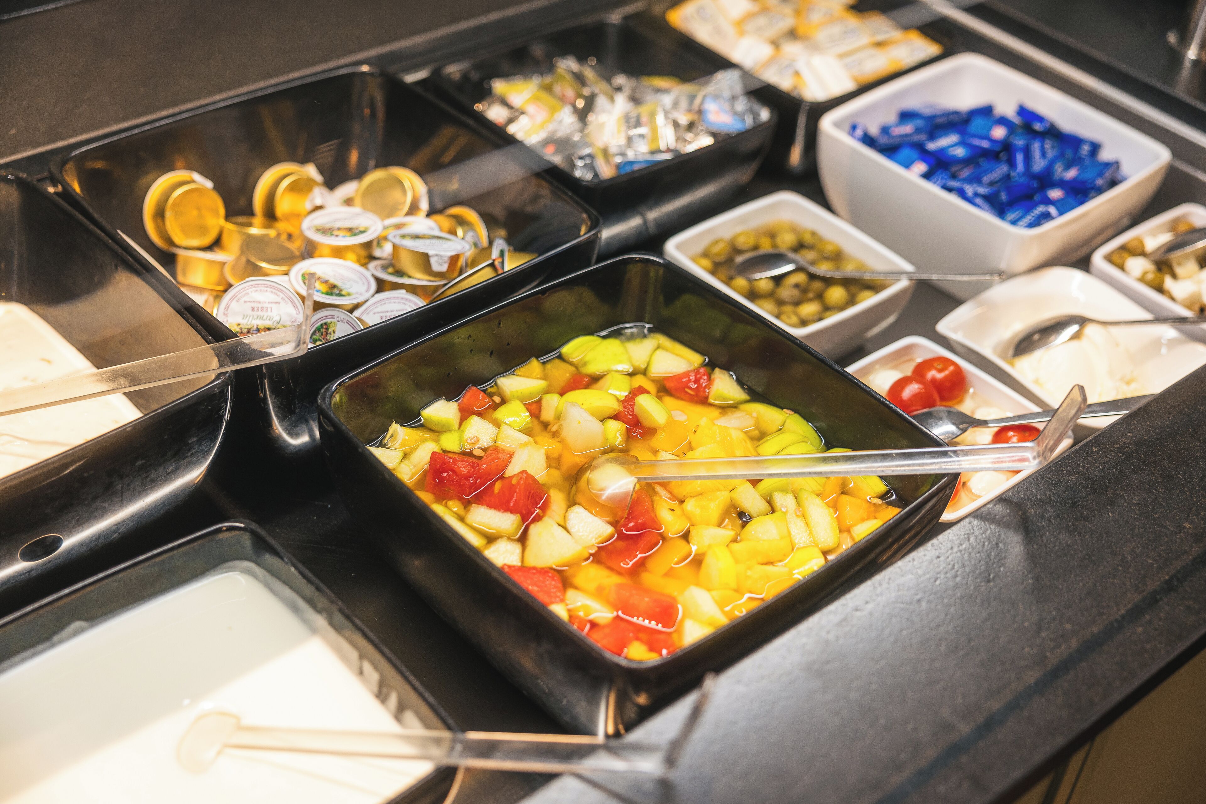 Un buffet proposant une variété d’aliments, notamment des fruits, des légumes et des condiments.