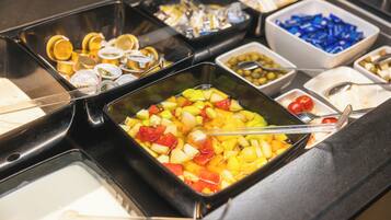 Un buffet proposant une variété d’aliments, notamment des fruits, des légumes et des condiments.