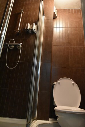 Un baño con ducha, inodoro y paredes de azulejos.