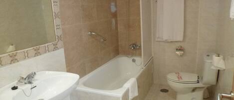 Un baño con bañera, lavamanos e inodoro.