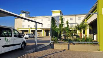 A Travelodge hotel with a covered parking area, a white van, and a building with a sign.