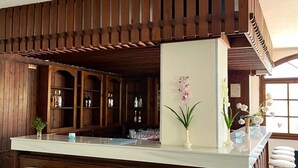 A bar area with wooden paneling, a white countertop, and three stools. - Theodorou Beach (Kos)