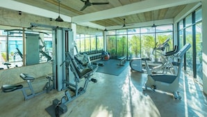 Un gimnasio amplio con diversos equipos de ejercicio, ventanas grandes y techo de madera.