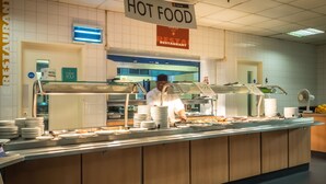 Zona de bufé con un cartel que indica 'COMIDA CALIENTE' y 'RESTAURANTE BANKSIDE'.