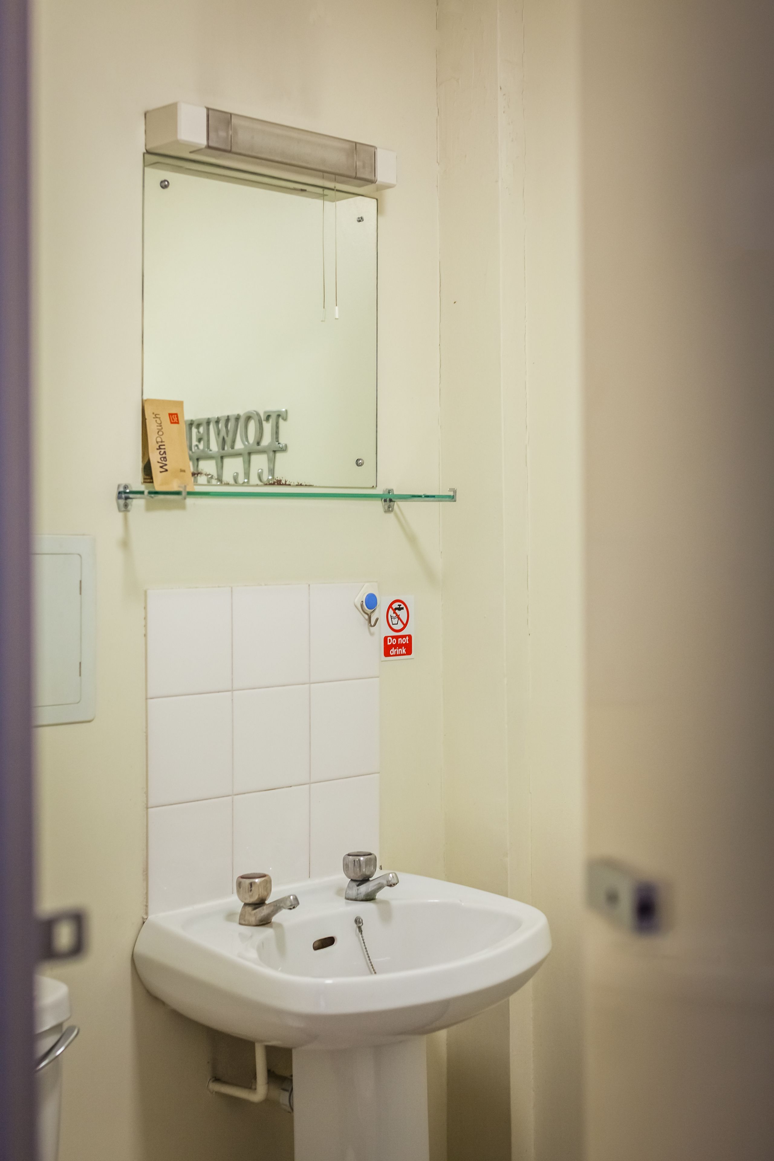 A bathroom with a white sink, a mirror, and a 'Do not drink' sign.