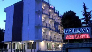 Un edificio de varios pisos con balcones y un letrero que dice "GALAXY ART HOTEL".